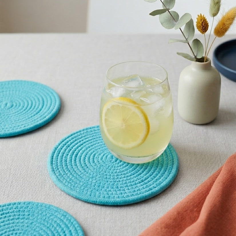 Portavaso artesanal Lilia Baez con diseño minimalista en color Azul turquesa. Accesorio de mesa en cordón enrollado con estética vibrante y sofisticada.